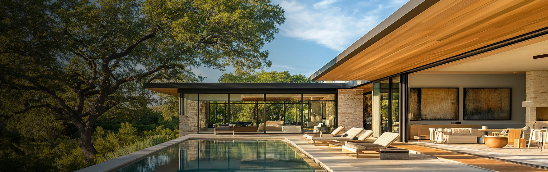 Luxury contemporary villa with infinity pool, large picture windows, and spacious terrace, surrounded by mature trees in a natural setting